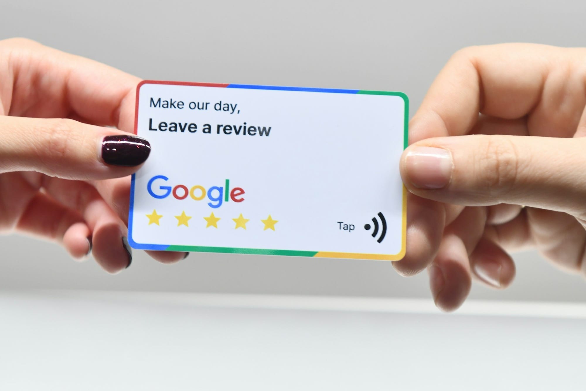 two hands holding a google credit card in front of an apple logo